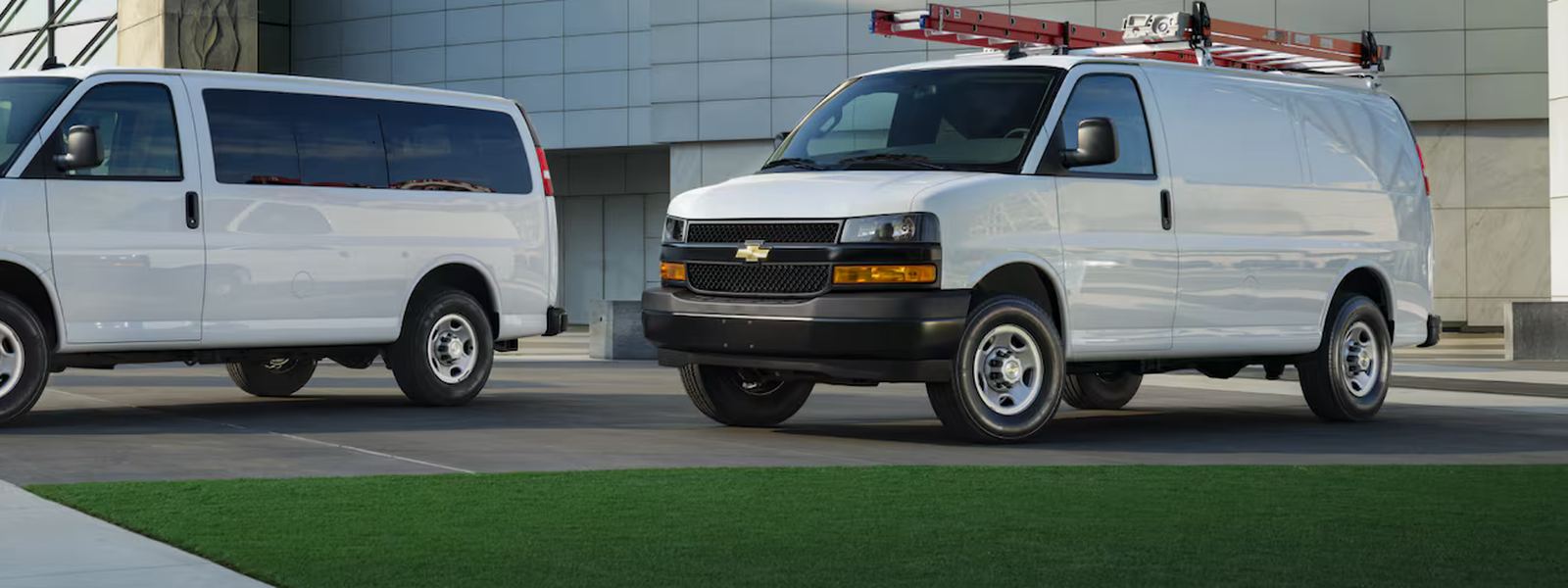 Chevrolet Express Cargo Van with a roof ladder rack, parked at a commercial building