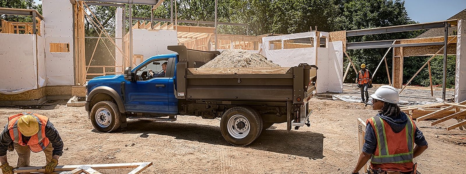 Ford Super Duty chassis cab with a loaded dump body at a residential construction site