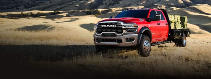 Ram chassis cab with a loaded flatbed body on open ground
